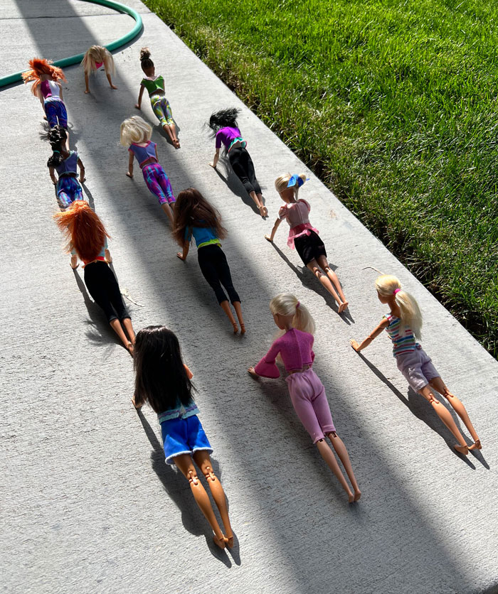 Dolls posed in yoga positions on a concrete surface, creating a funny scene inspired by hilarious-kids' creativity.