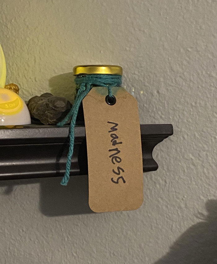 A small jar labeled "madness" on a shelf, featuring a turquoise string, showcasing a hilarious kids' idea.