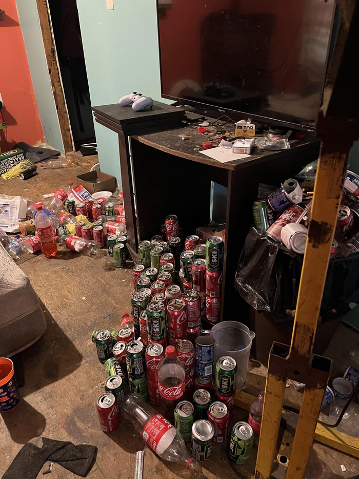 Cluttered room with numerous soda cans and bottles scattered on the floor, highlighting horrible roommates.