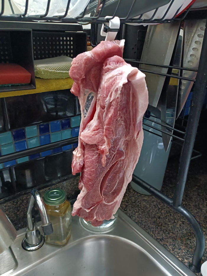 Raw meat hanging over a sink, exemplifying horrible roommates' unusual kitchen habits.