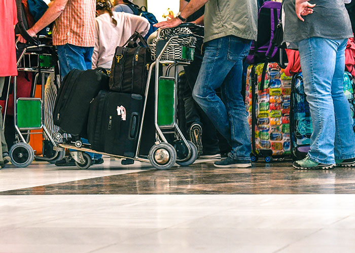 People waiting with luggage carts in a busy airport, highlighting normal things that are unexpectedly horrific.