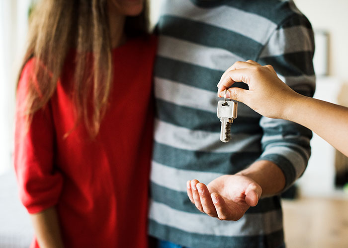 Couple receiving house key, a normal moment with underlying implications.