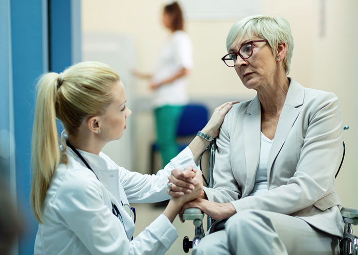 A doctor comforts an elderly patient in a wheelchair, highlighting the normal yet potentially horrific aspects of healthcare.