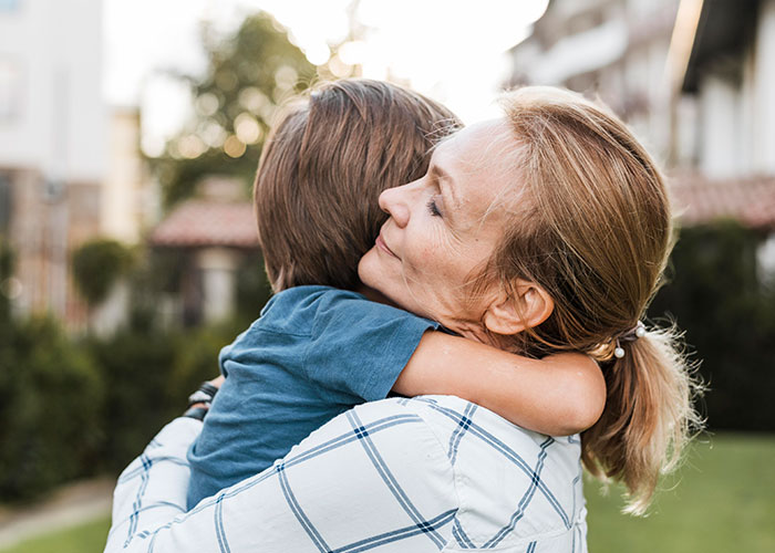 A woman hugging a child outdoors, illustrating normal things with hidden depth.