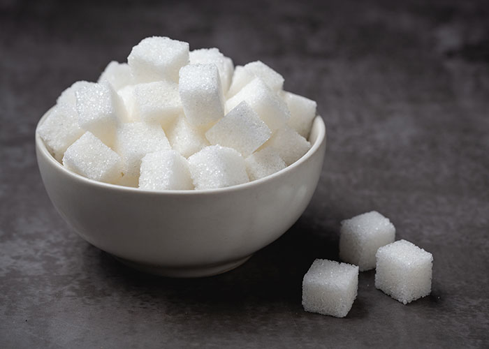 Bowl of white sugar cubes on a gray surface, symbolizing normal things that can be pretty horrific.