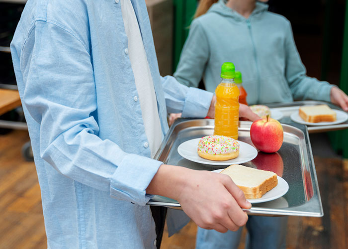 Person holding a tray with a sandwich, donut, apple, and juice, illustrating normal things that might be horrific on reflection.