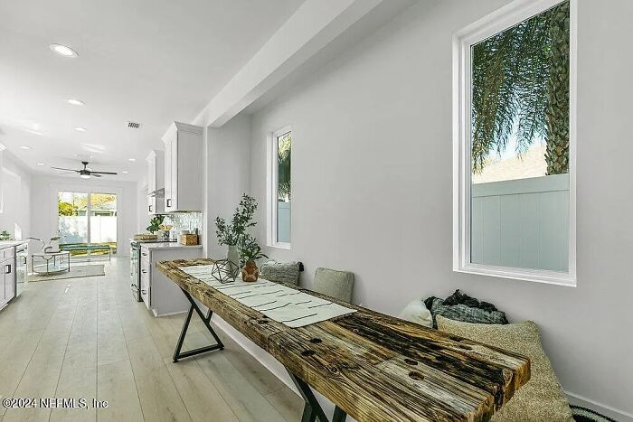 Modern Florida home interior with rustic wooden table and large windows overlooking a small neighbor's yard.