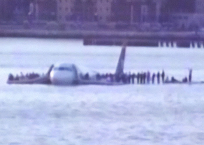 Plane in water with people standing on wings; related to Captain Sully's theory on DC crash visibility issue.