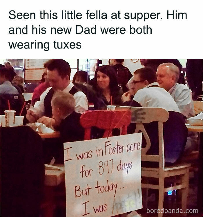 A child in a restaurant with his new dad, both in tuxedos, next to a heartfelt adoption announcement sign.