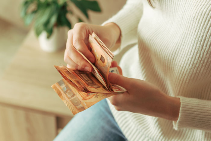 Woman counting euros, considering legal action due to unpaid family bill.