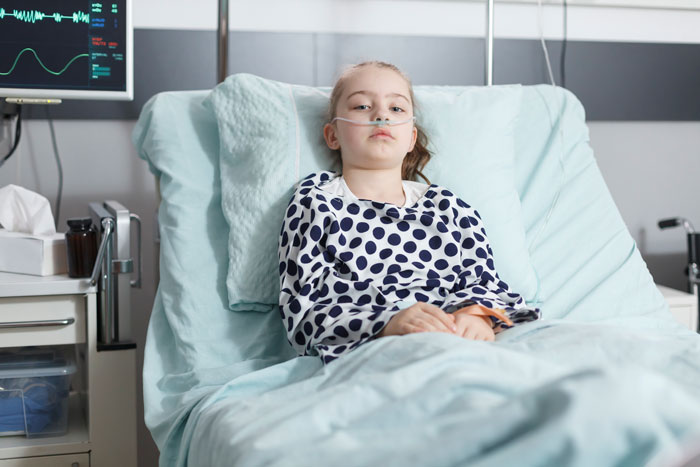 Child in hospital bed with medical equipment, related to a family's unpaid bill.