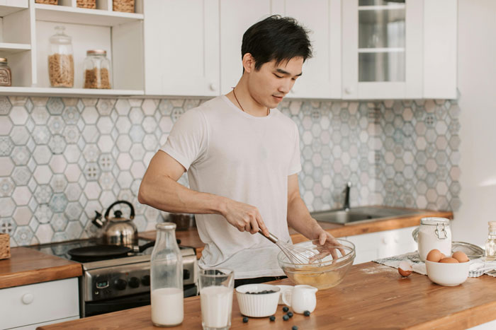 Young man whisking ingredients in a modern kitchen for a cooking drama.