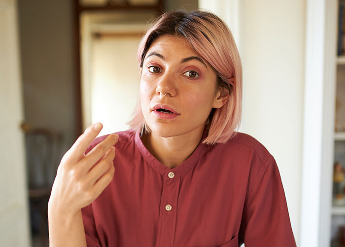 Woman looking tired and frustrated, wearing a maroon shirt, discussing relationship issues due to her boyfriend's snoring.