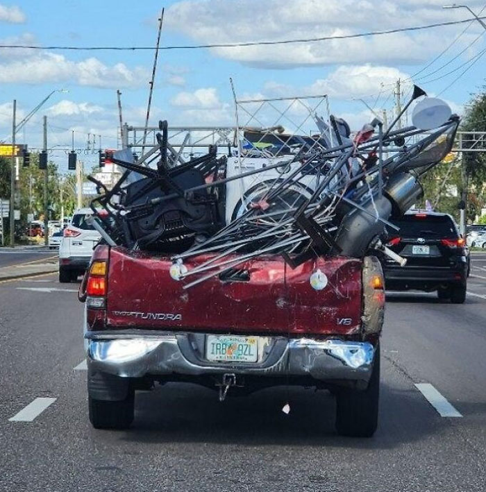 Overloaded truck on a busy road with unsecured items, illustrating typical "Idiots in Cars" scenario.