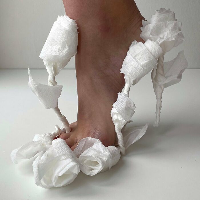 Sculptural footwear made from twisted and styled paper, resembling an artistic sandal design.