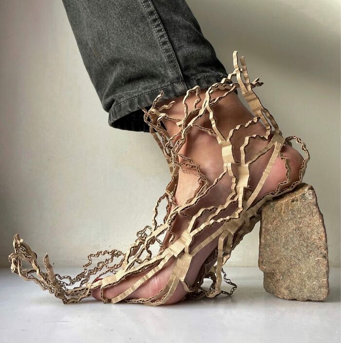 Sculptural footwear made from cardboard and stone, resembling a unique artistic shoe design.