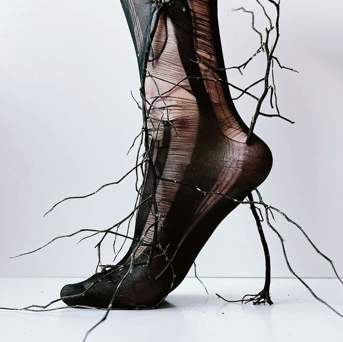 Sculptural footwear made with branches and black tights, blending everyday objects into art.