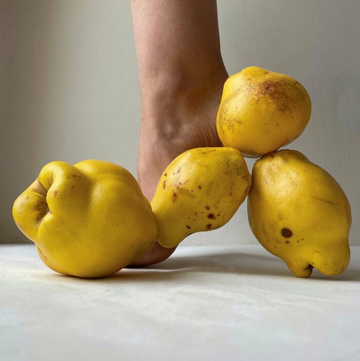 Foot wearing sculptural footwear made from yellow fruits, showcasing creative concept by the artist using everyday objects.