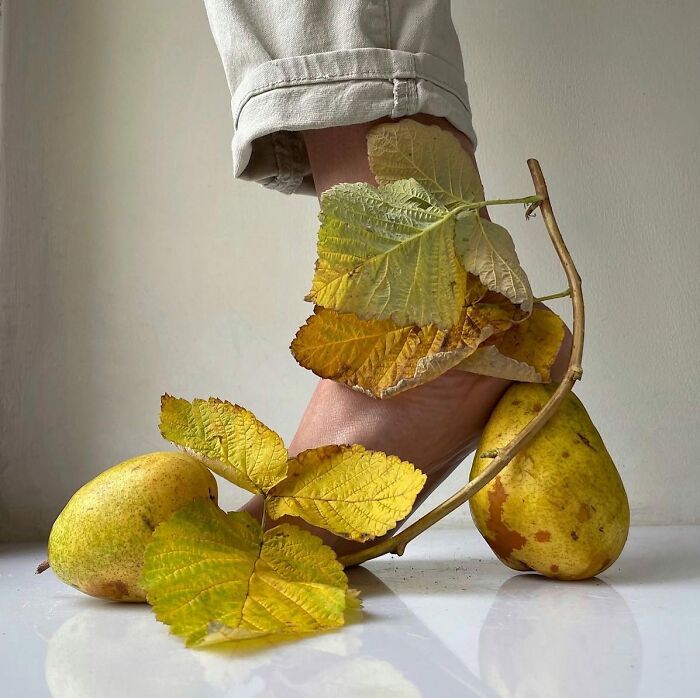 Bare foot adorned with sculptural footwear made from pears and leaves.