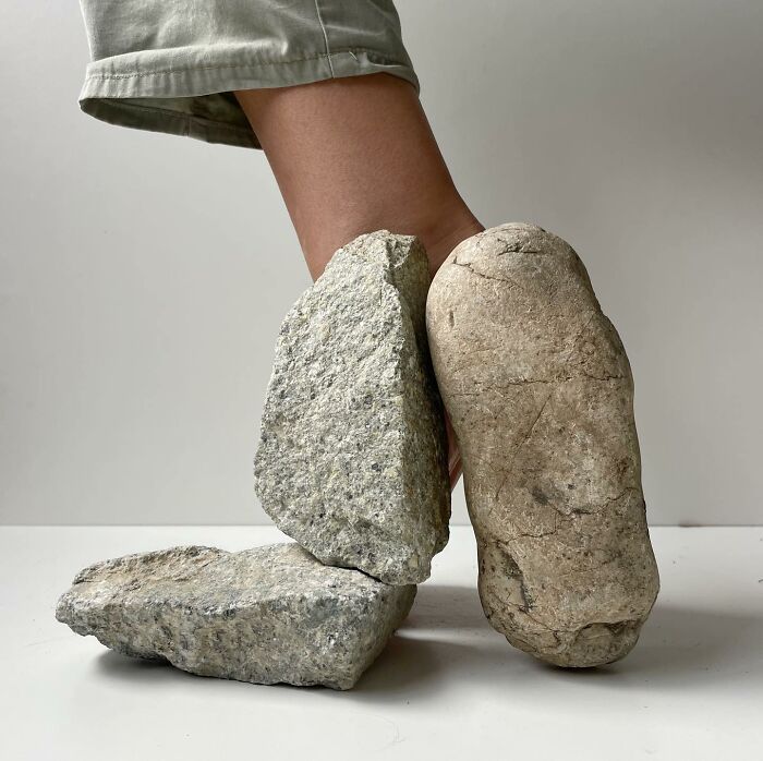 Foot with sculptural footwear made from rocks, showcasing creative use of everyday objects in art.