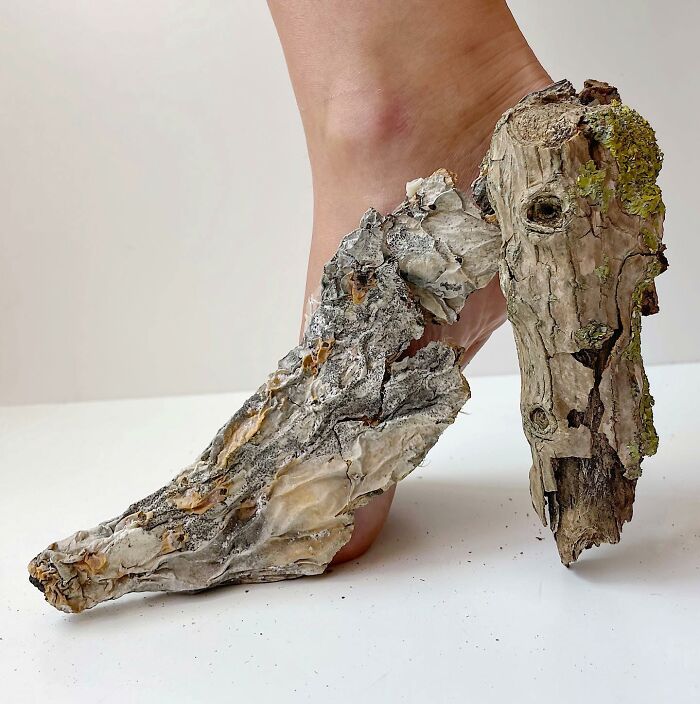 Bare foot wearing sculptural footwear made from textured bark, showcasing creative use of everyday objects.