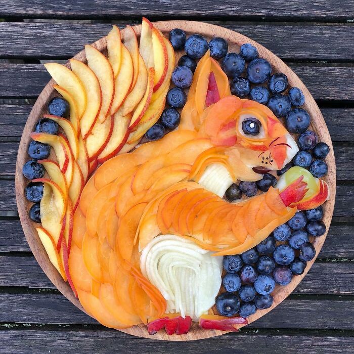 Plate of fruit arranged as a squirrel, featuring healthy eating as an art form with blueberries and sliced peaches.