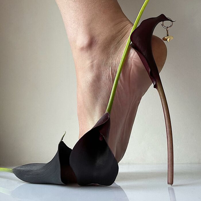 Footwear sculpture crafted from dark flowers, showcasing creative use of everyday objects in design.