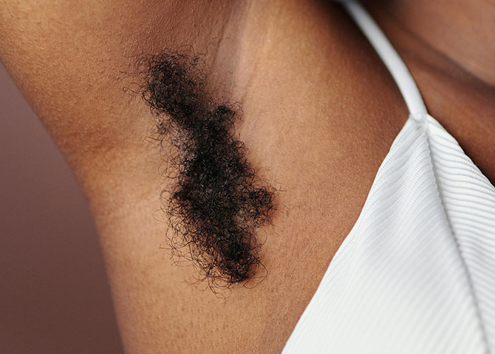 Close-up of a woman's armpit with natural hair growth, celebrating self-acceptance and body positivity.