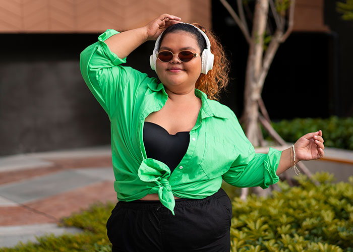 Woman confidently wearing a green shirt and headphones, embracing her style and individuality.