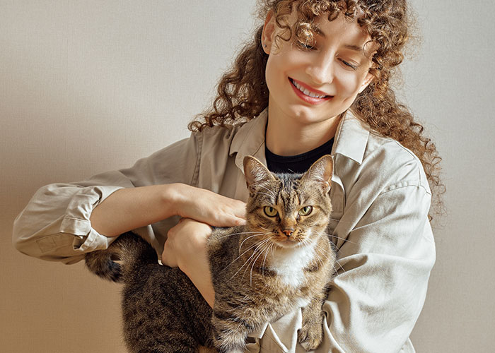 Woman smiling, embracing a cat, celebrating self-love.