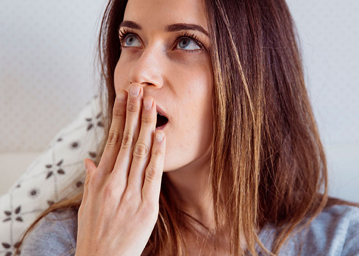 Woman with hand over mouth, expressing herself confidently despite societal norms.