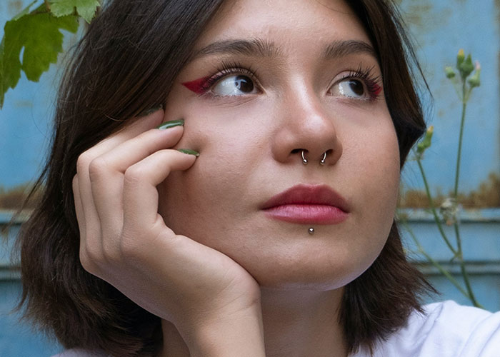 Woman with unique piercings and makeup, confidently embracing her individual style.