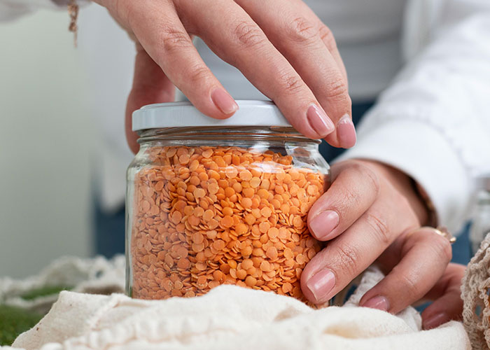 Hands holding a jar of orange lentils, symbolizing self-love and defying societal norms for women.