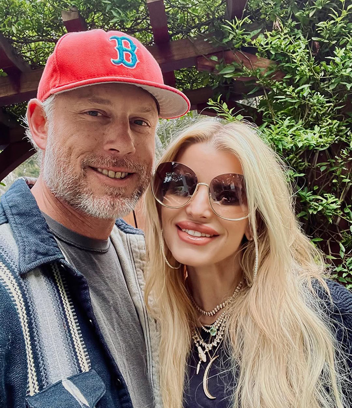 Two people smiling outdoors, one wearing a red cap, the other with sunglasses, emphasizing "revenge body" style.