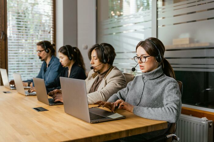 Office workers with headsets at laptops.