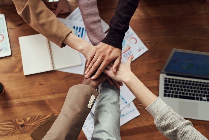 Hands stacked over a conference table.