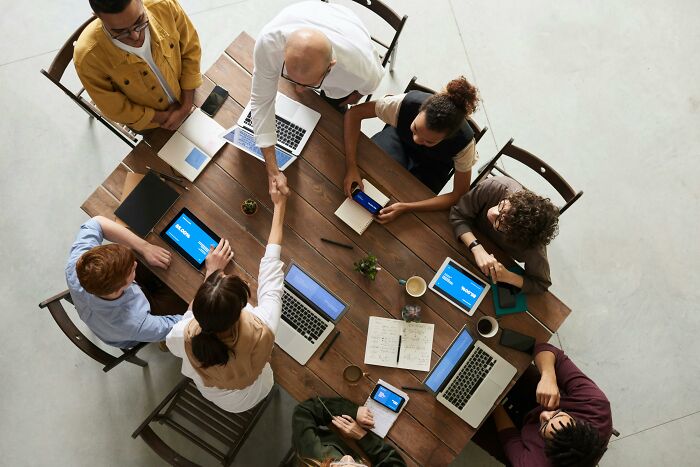 Team meeting, working on laptops around a wooden table.