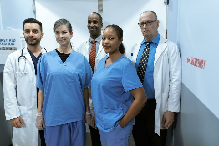 Medical team standing in a hospital corridor, wearing scrubs and lab coats.