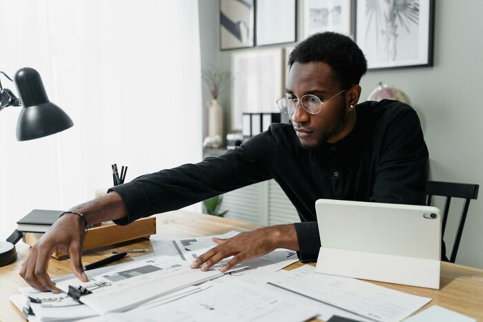 Person working at a desk with papers and a tablet, focused on a task.