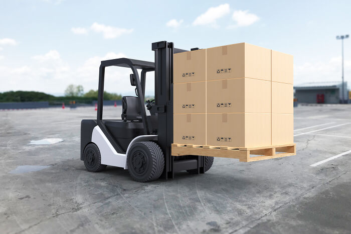 Forklift transporting boxes on a warehouse lot.