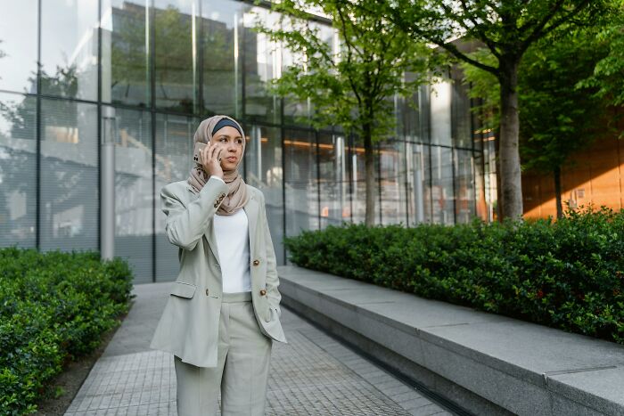 Woman in business attire on phone outside an office building.