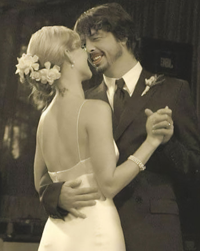 A couple dancing together at their wedding, bride wearing flowers in her hair, groom in a suit, symbolizing their joyous moment.