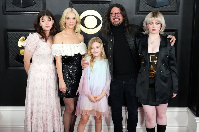 Jordyn Blum with Dave Grohl and family at an event, all dressed elegantly in front of a decorated backdrop.