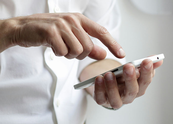 Hands holding a smartphone, suggesting strange human behavior and curiosity in a courtroom setting.