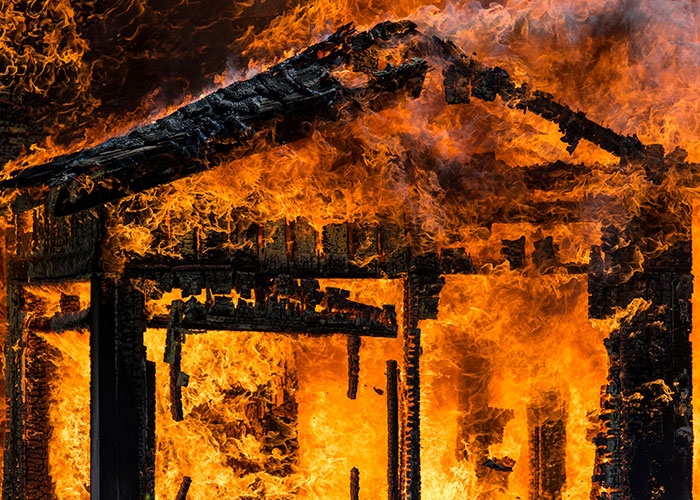 House engulfed in flames, showcasing strange human behavior as a legal case unfolds.