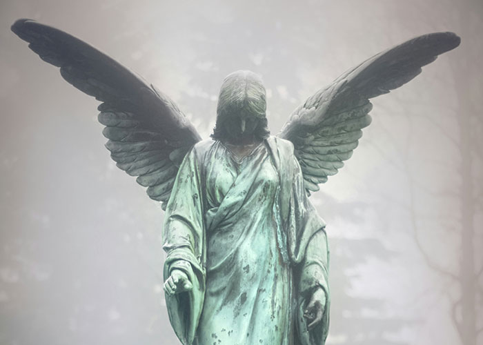 An angel statue with wings, shrouded in mist, symbolizing mysterious human behavior.