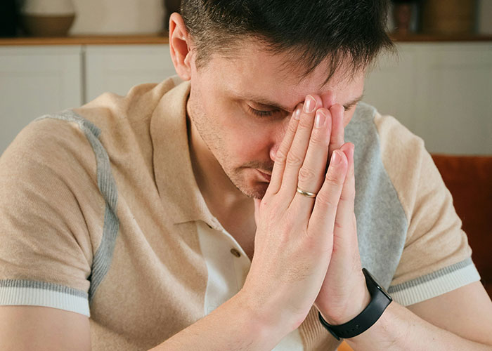 Person deep in thought with hands clasped, showcasing strange human behavior.