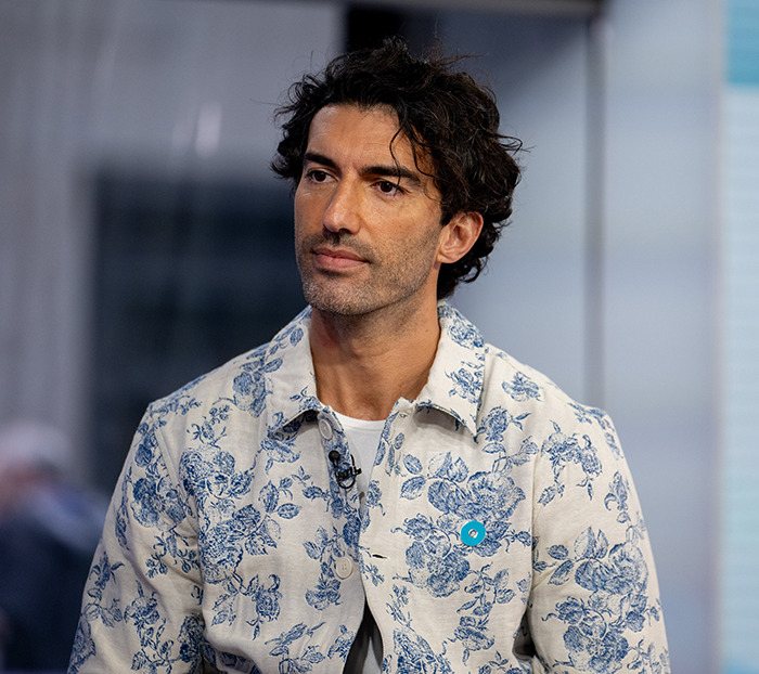 Man in a floral shirt, serious expression, sitting indoors.