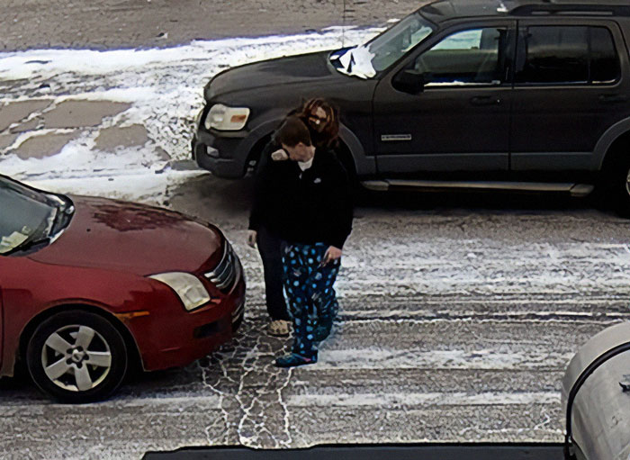 People standing between two parked vehicles in a snowy setting, relating to road rage incident.