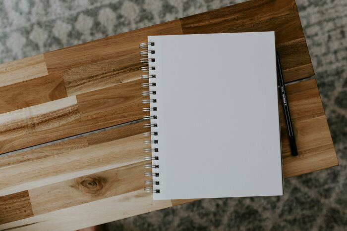 A blank notebook and pen on a wooden table, ready for jotting down secrets.